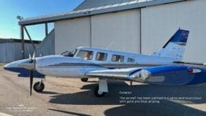 A Piper Seneca III PA-34-220T aircraft with registration SE-LCA parked in front of a hangar, showing the white and blue paint scheme.