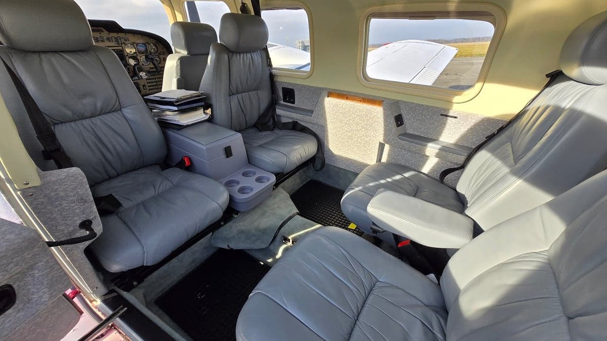 The aircraft's interior features gray leather seats and a center console with cupholders.
