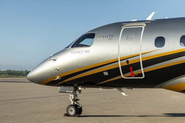 A close-up of the nose and front fuselage of the Embraer Legacy 500, showing the silver and black paint with yellow accents.
