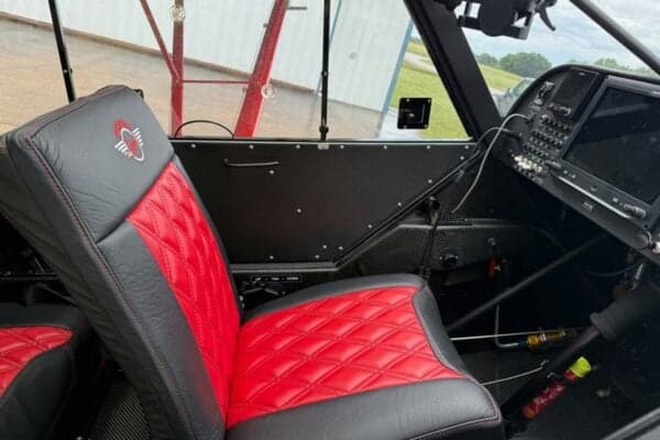 View of the cockpit showing the instrument panel and red and black leather seat.