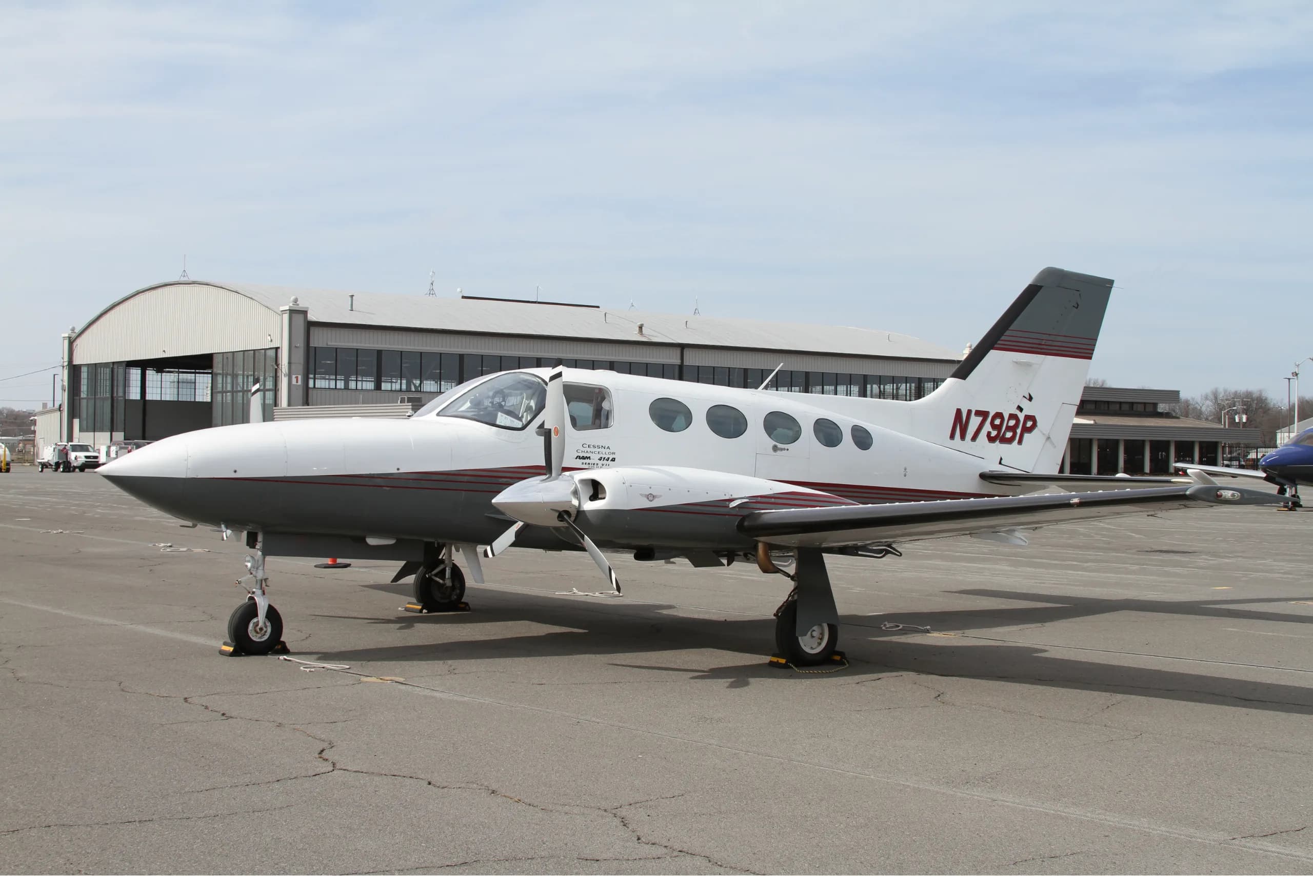 A Cessna aircraft parked on the tarmac in front of a hangar.