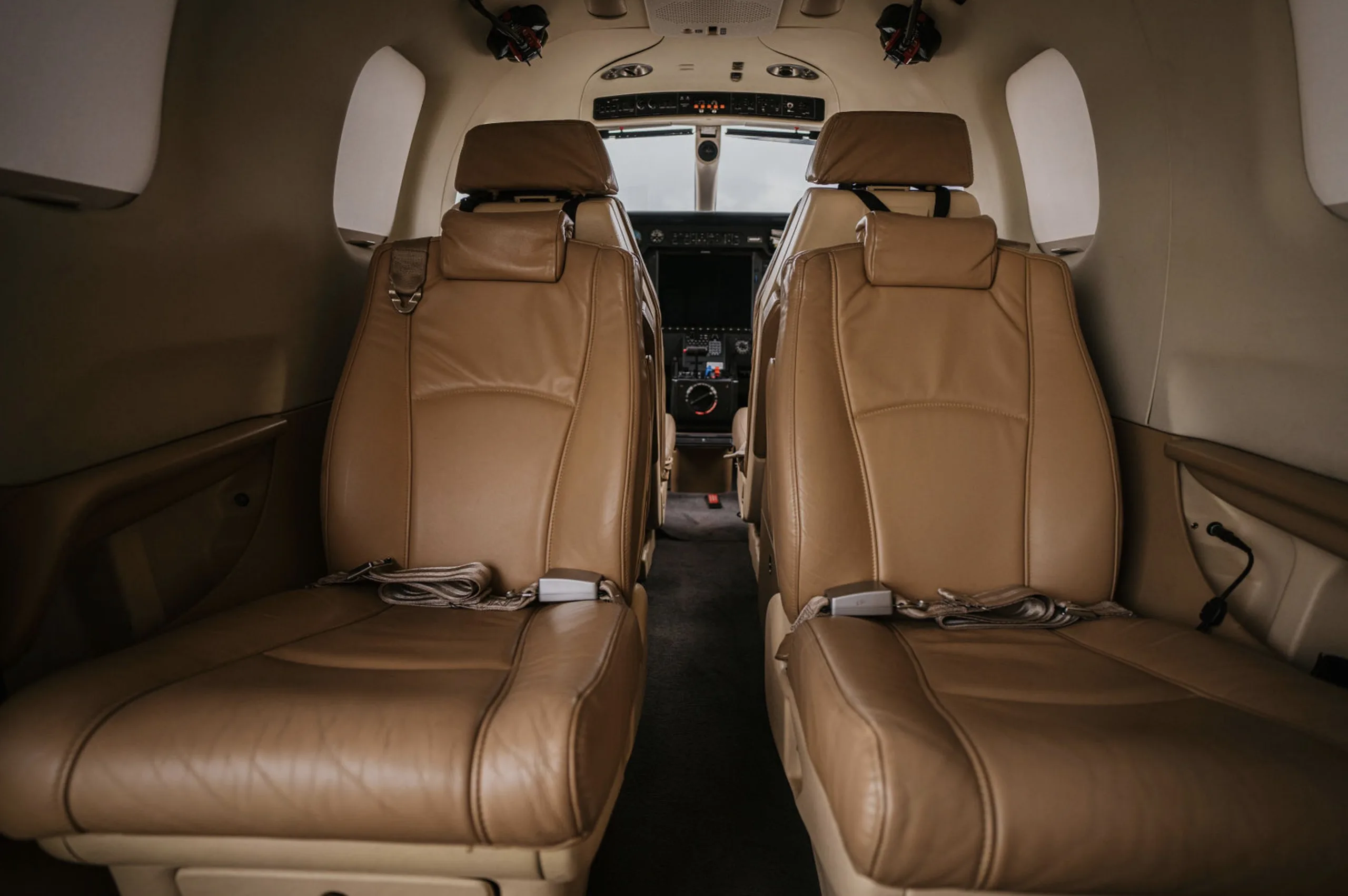 Interior view of the aircraft cabin showing the front two tan leather seats.