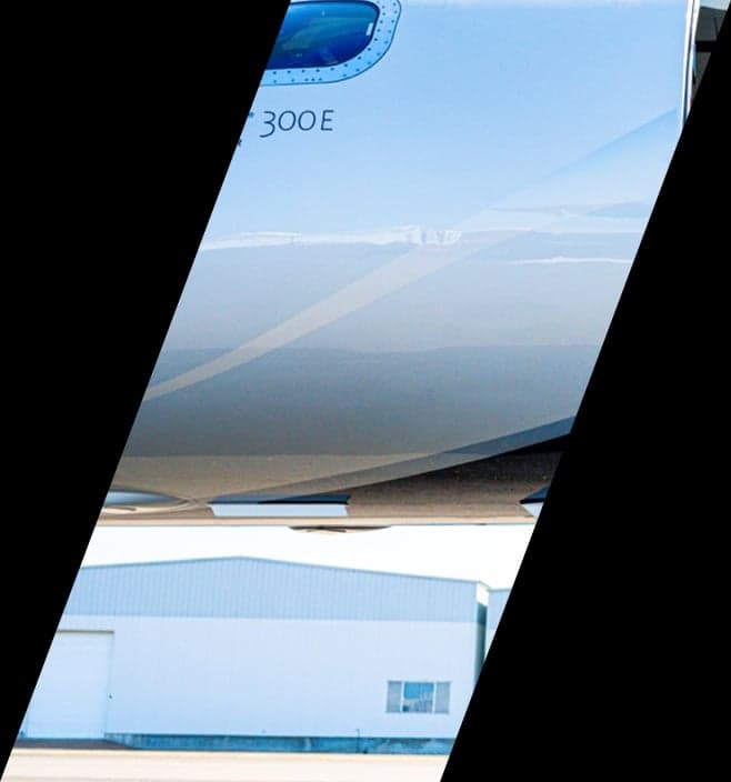 Close-up of the white fuselage of an Embraer Phenom 300E jet.