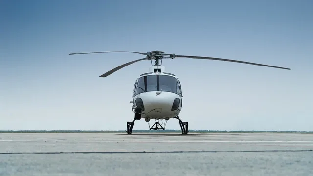 Front view of a white helicopter with skids parked on an airfield.