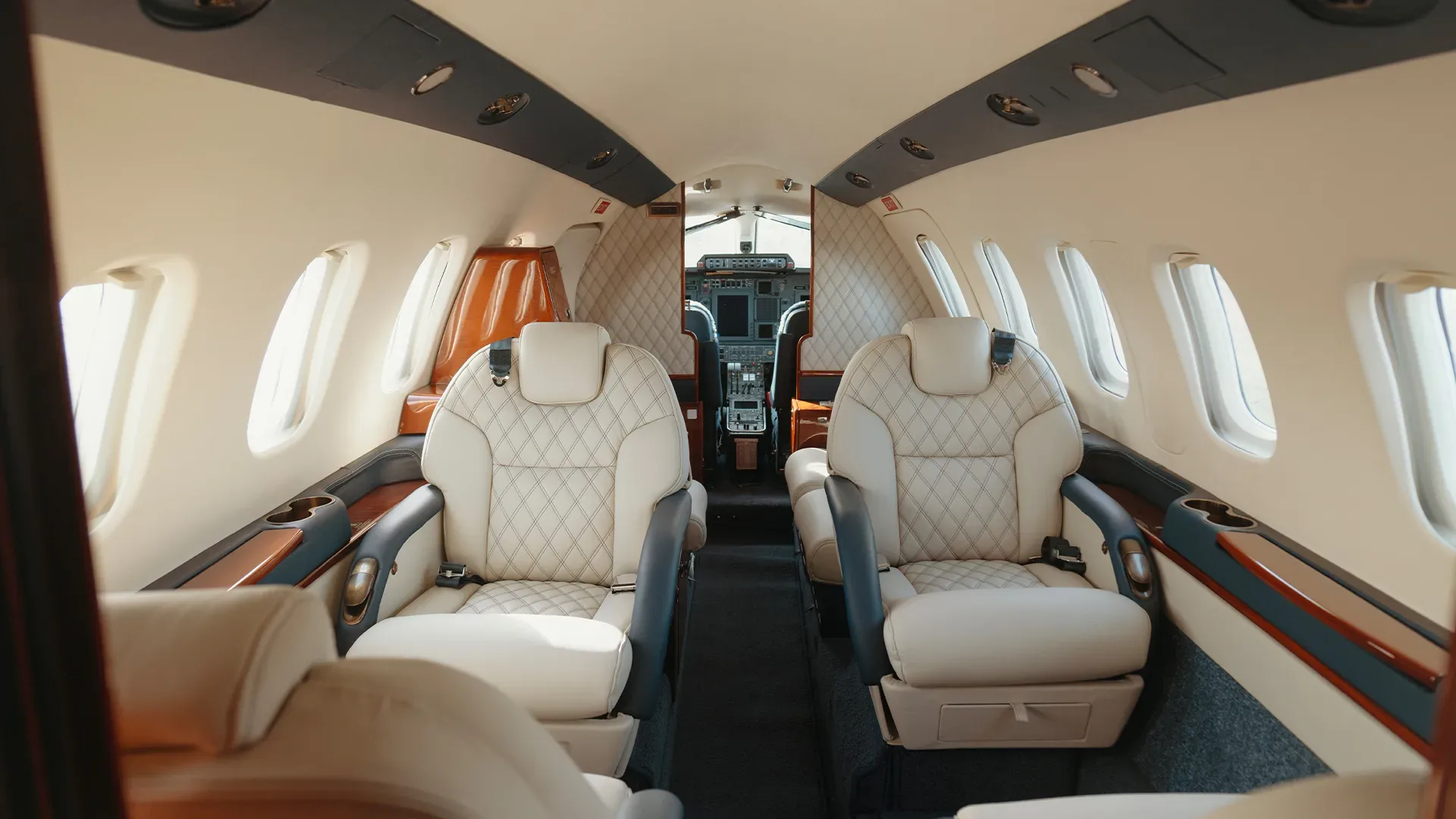 The interior of the aircraft features cream-colored leather seats and wood trim.