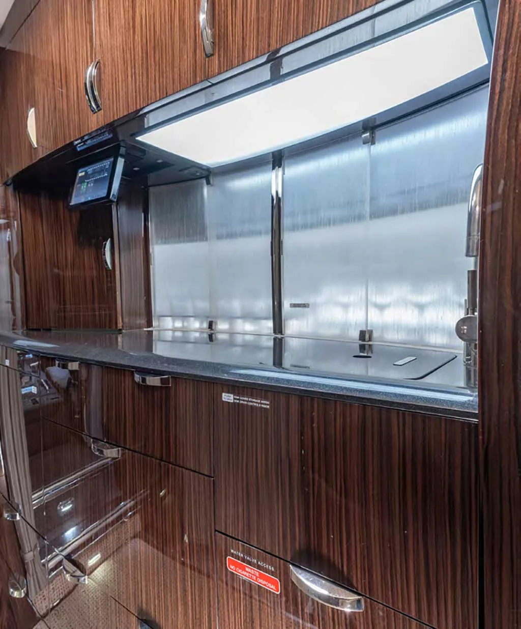 A detailed view of the aircraft's galley, featuring dark wood cabinetry, a sink, and a polished countertop.