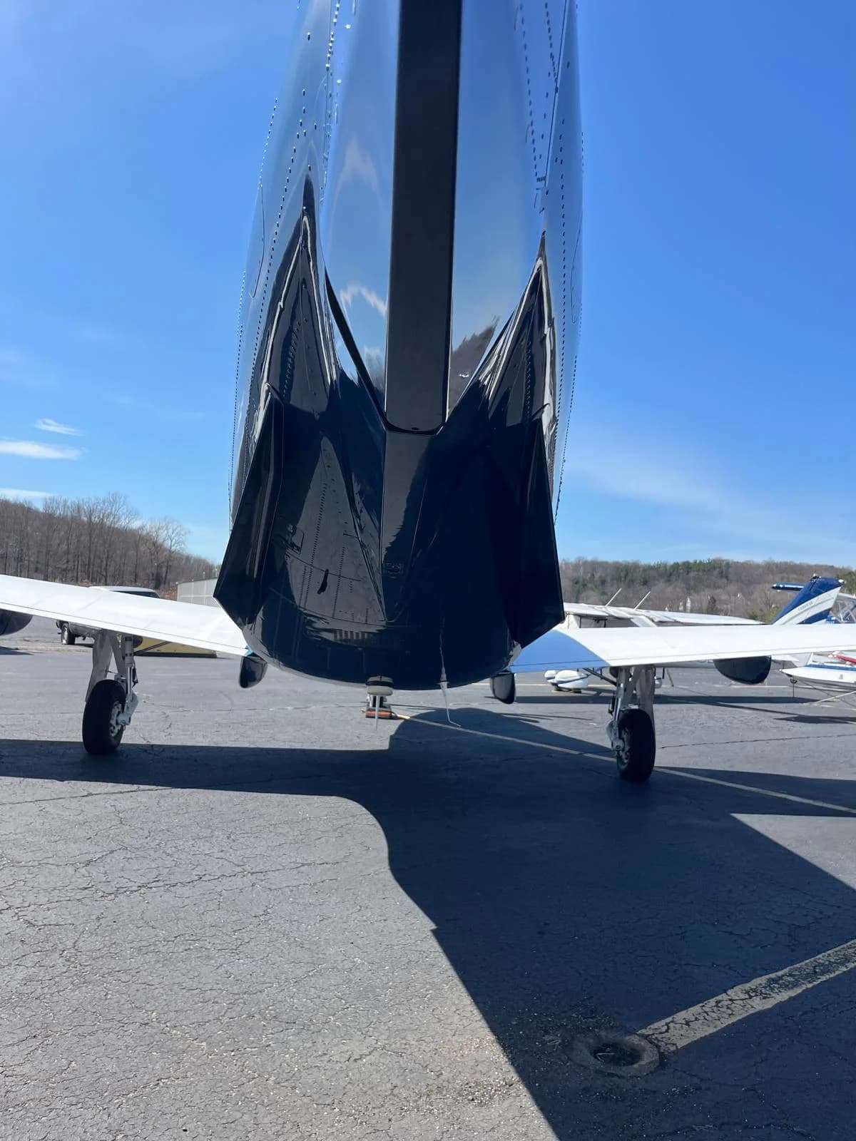 A low-angle rear view of the Pilatus PC-12 aircraft on a tarmac under a clear blue sky.