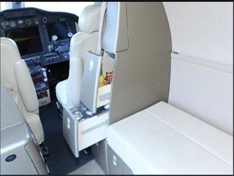 The interior of the aircraft cabin, including seats and a refrigerator.
