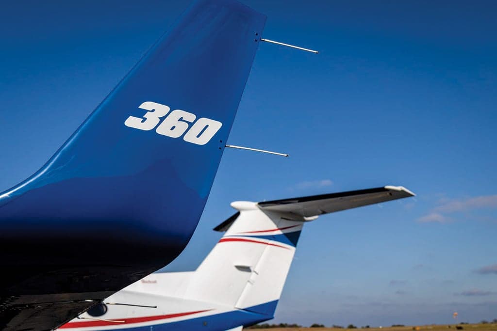 Close-up of the blue tail of a King Air 360, showing the "360" text and part of another aircraft's tail in the background.