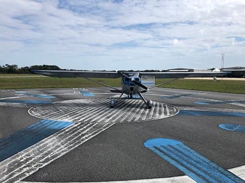 Side view of a silver and blue aircraft on a tarmac.