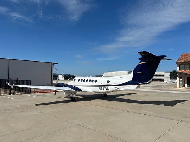 King Air aircraft N711VN parked on the tarmac in front of a hangar.
