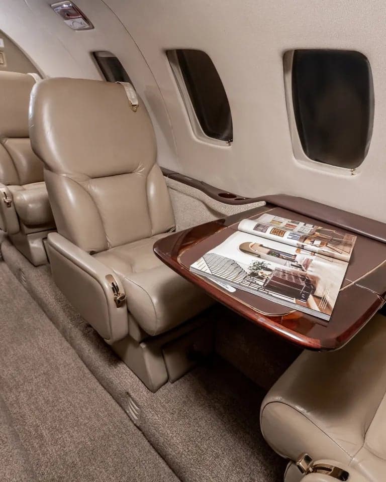 View of the aircraft interior showing a seat with a table and magazine.