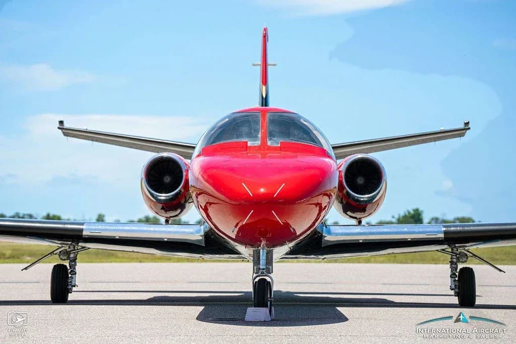 A head-on view of the red and black Cessna Citation V (N300CH) jet on a tarmac under a clear sky.