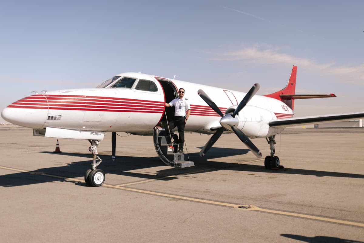 Side view of a white and red Beechcraft King Air aircraft with a pilot standing on the steps.