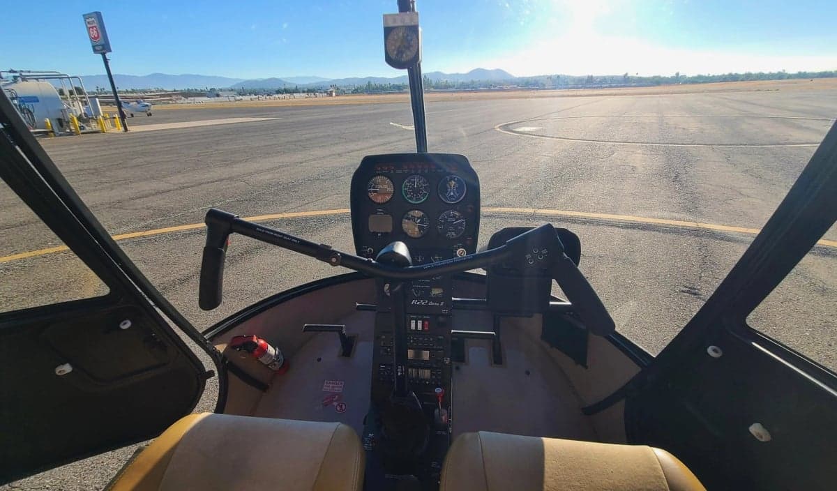 A direct view of the instrument panel and controls in the cockpit of a Robinson R22 helicopter.