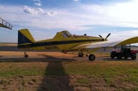 Yellow and blue agricultural aircraft parked on a runway.