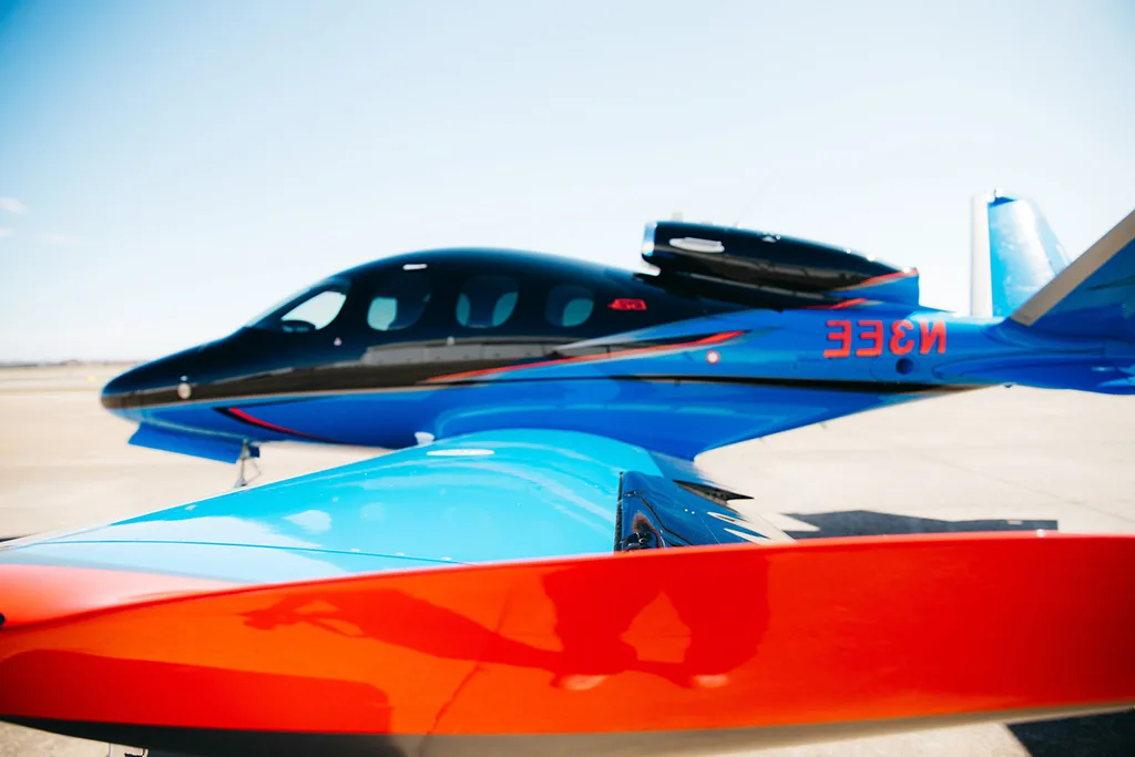 A close-up side view of a black and blue Cirrus Vision Jet (SF50) showing the registration "33CN" on the tail.