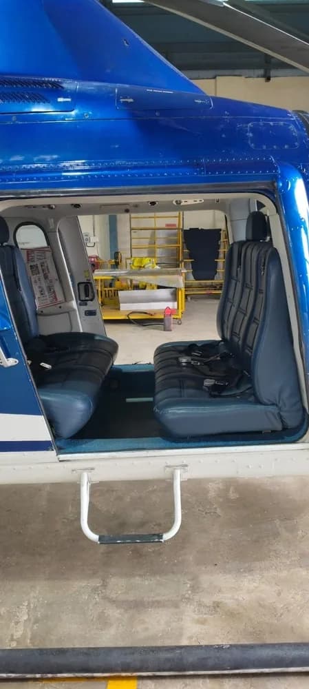 View of the blue leather passenger seats inside the helicopter cabin, looking towards the cockpit.