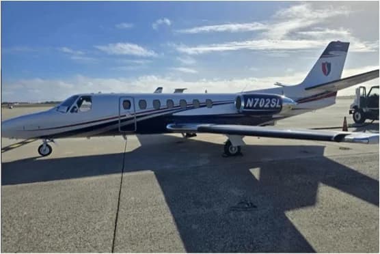 A Cessna Citation business jet, registration N702SL, with a silver and blue paint scheme, parked on an airport tarmac.