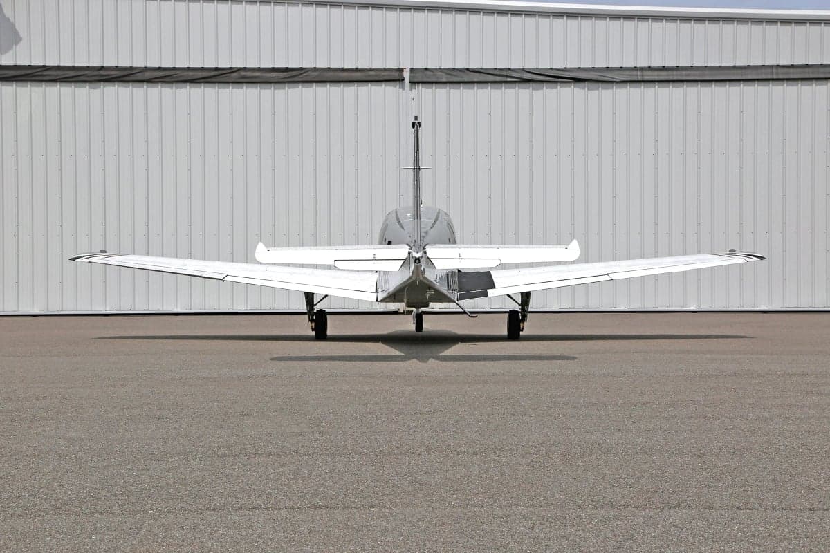 Rear view of a white and silver Beechcraft Bonanza on the tarmac.