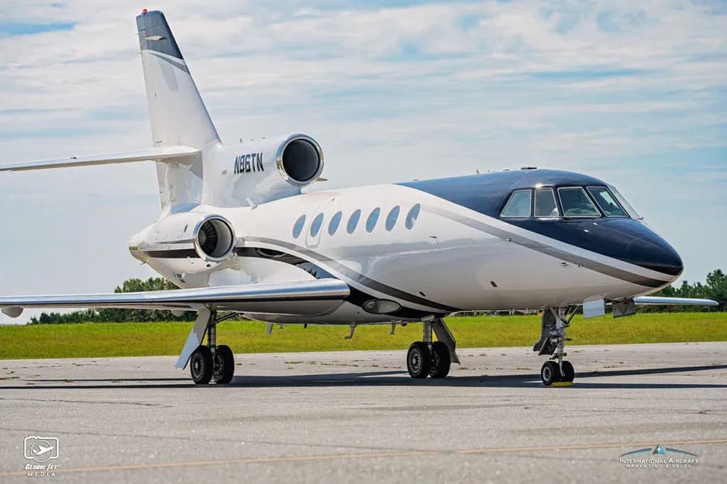A Dassault Falcon 900EX business jet, registration N86TN, parked on an airfield, viewed from the front-left.