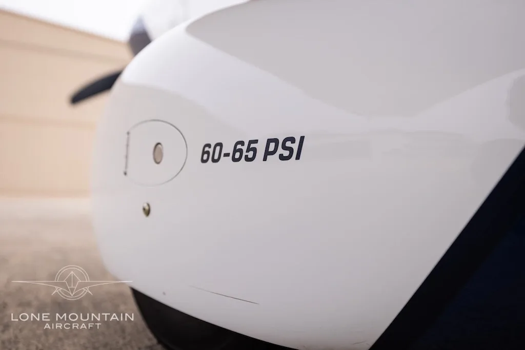 A close-up of the aircraft's white cowling showing "60-65 PSI" text.
