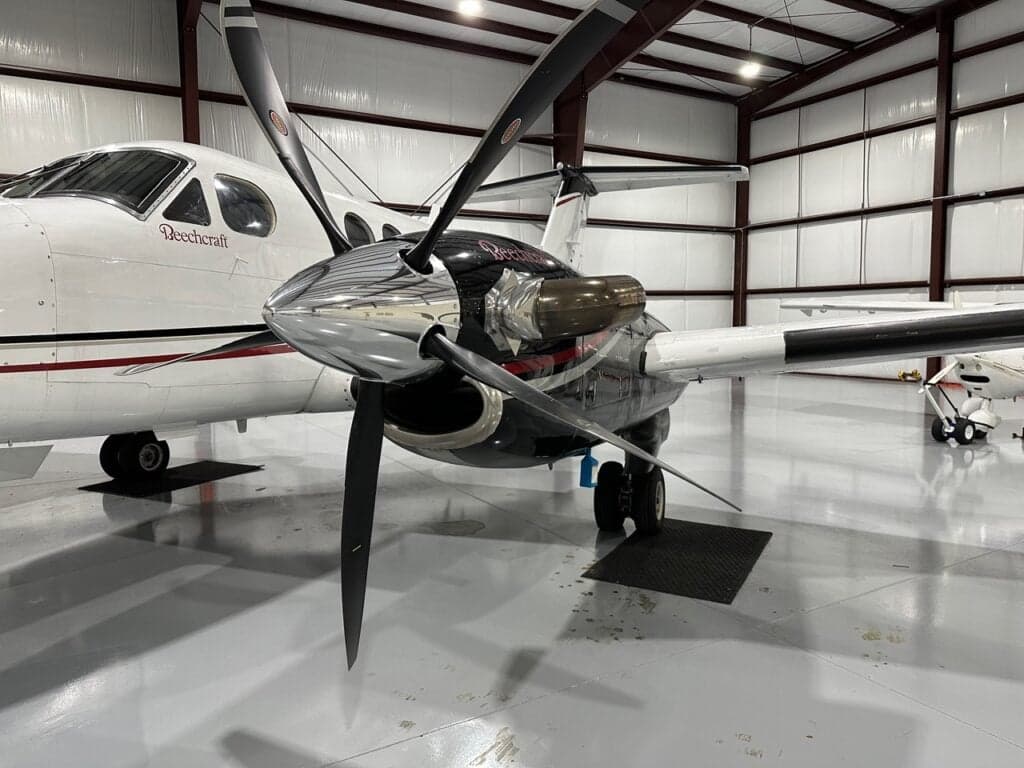 A close-up view of the right engine and propeller of a white Beechcraft King Air, showing the 'Beechcraft' logo on the fuselage.