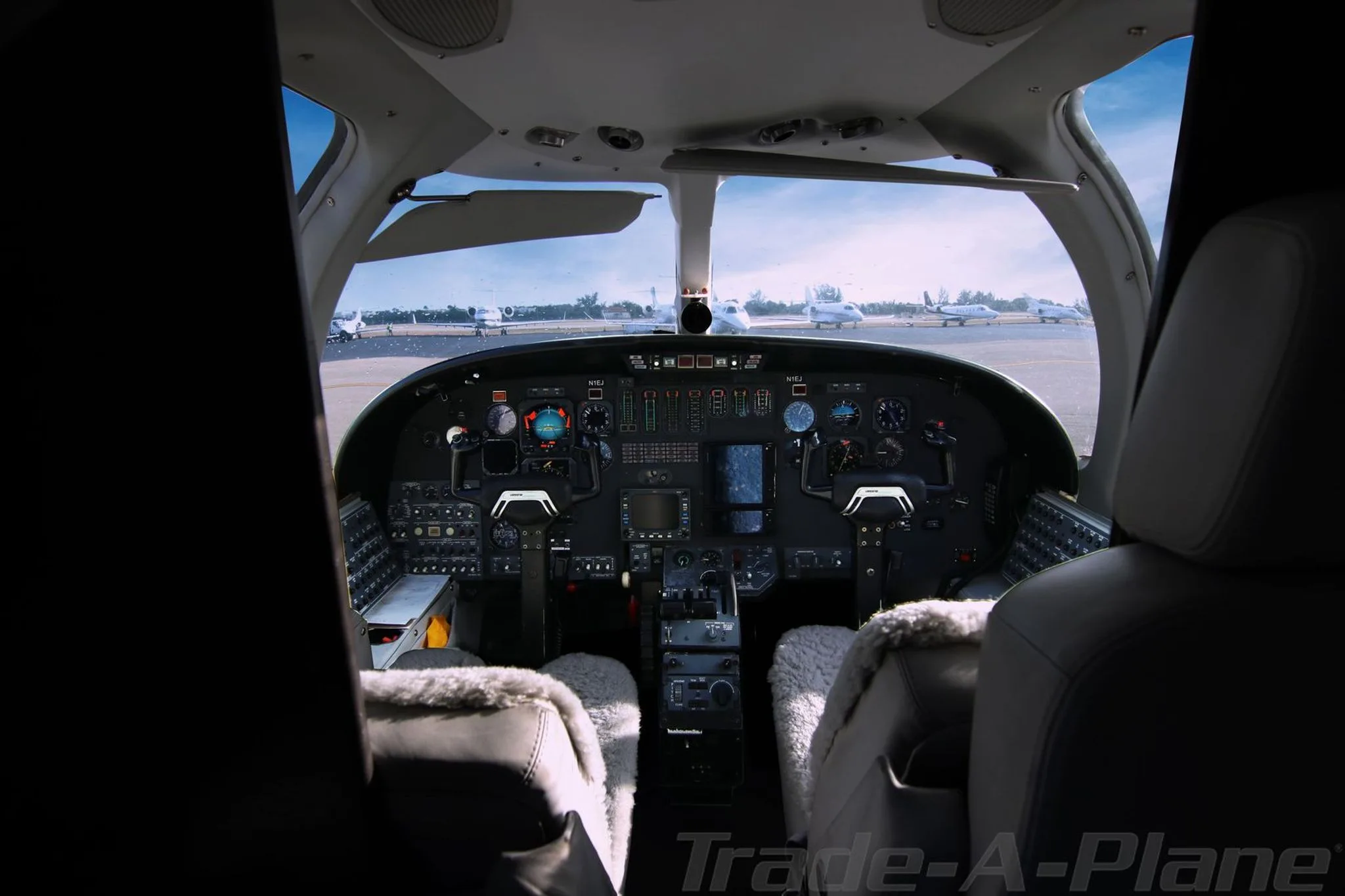 View from the cabin into the cockpit of a Cessna CitationJet, showing the instrument panel and controls.
