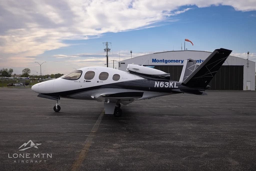 A white and black Cirrus Vision Jet (N63KL) parked on an asphalt apron in front of a hangar labeled "Montgomery County".