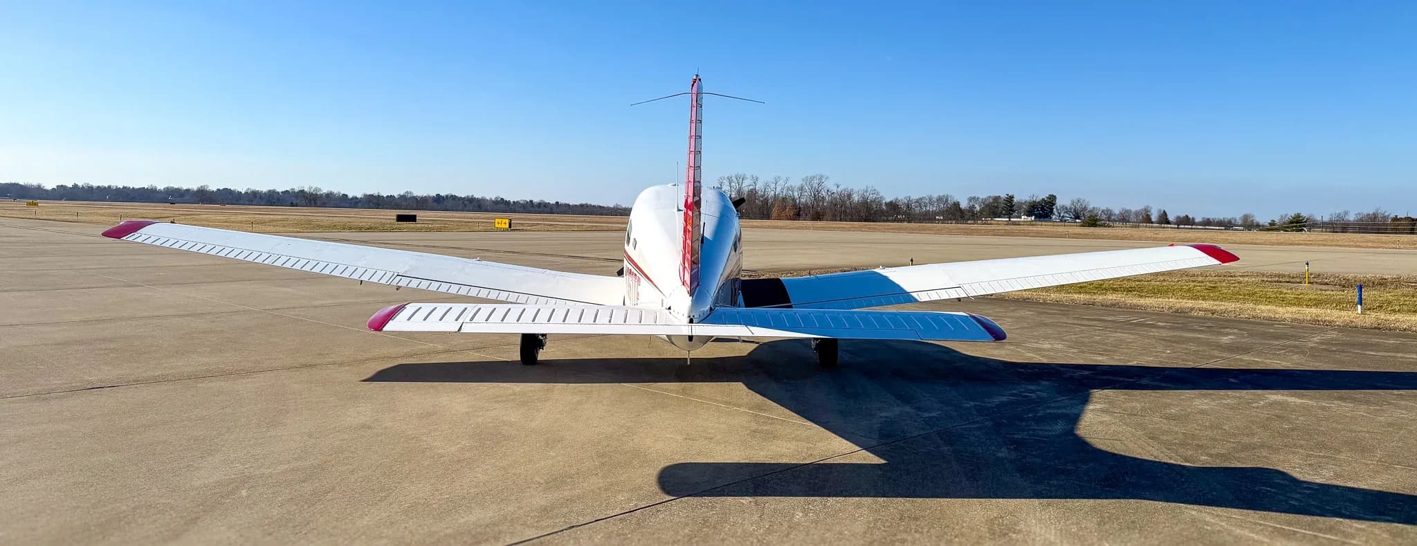 A rear view of a red and white Piper Archer TX aircraft, tail number N161TF, parked on an asphalt tarmac.