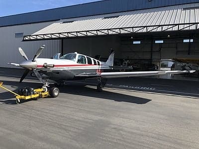 A Beechcraft Bonanza parked in front of a hangar.