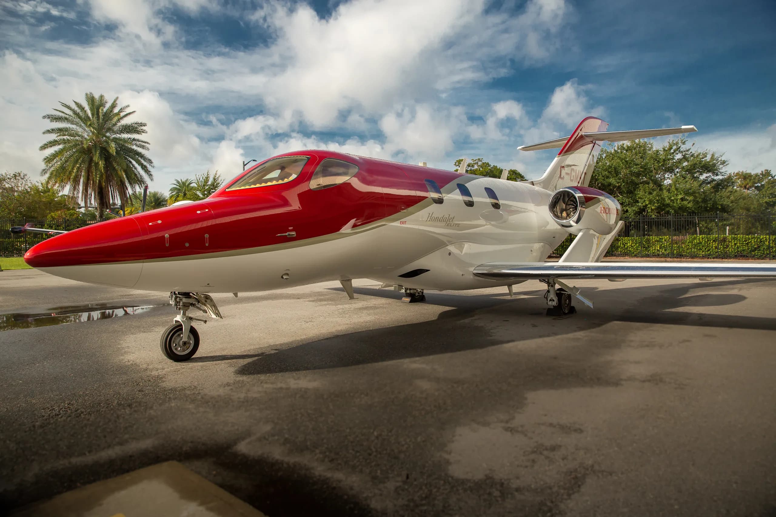 A red and white HondaJet with registration C-GMKT parked on an tarmac, viewed from the side.