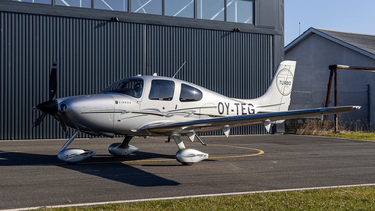 Side view of the silver Cirrus OY-TEG on the tarmac.