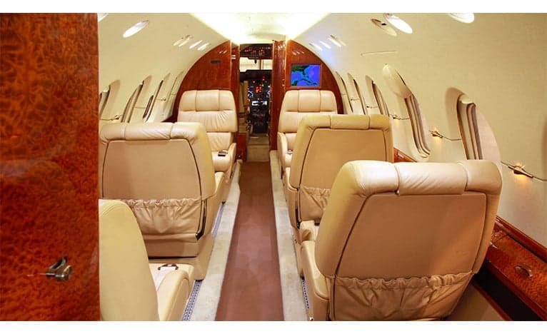 The interior of a Hawker jet with leather seats and wood paneling.