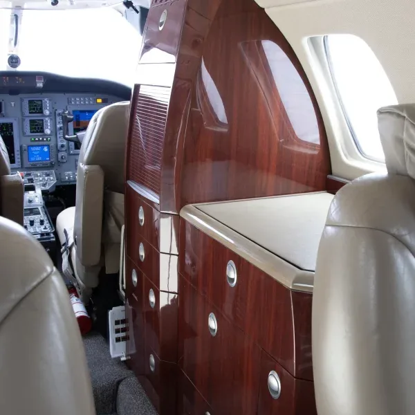 A view of the aircraft's dark wood interior cabinetry and the cockpit from the cabin.