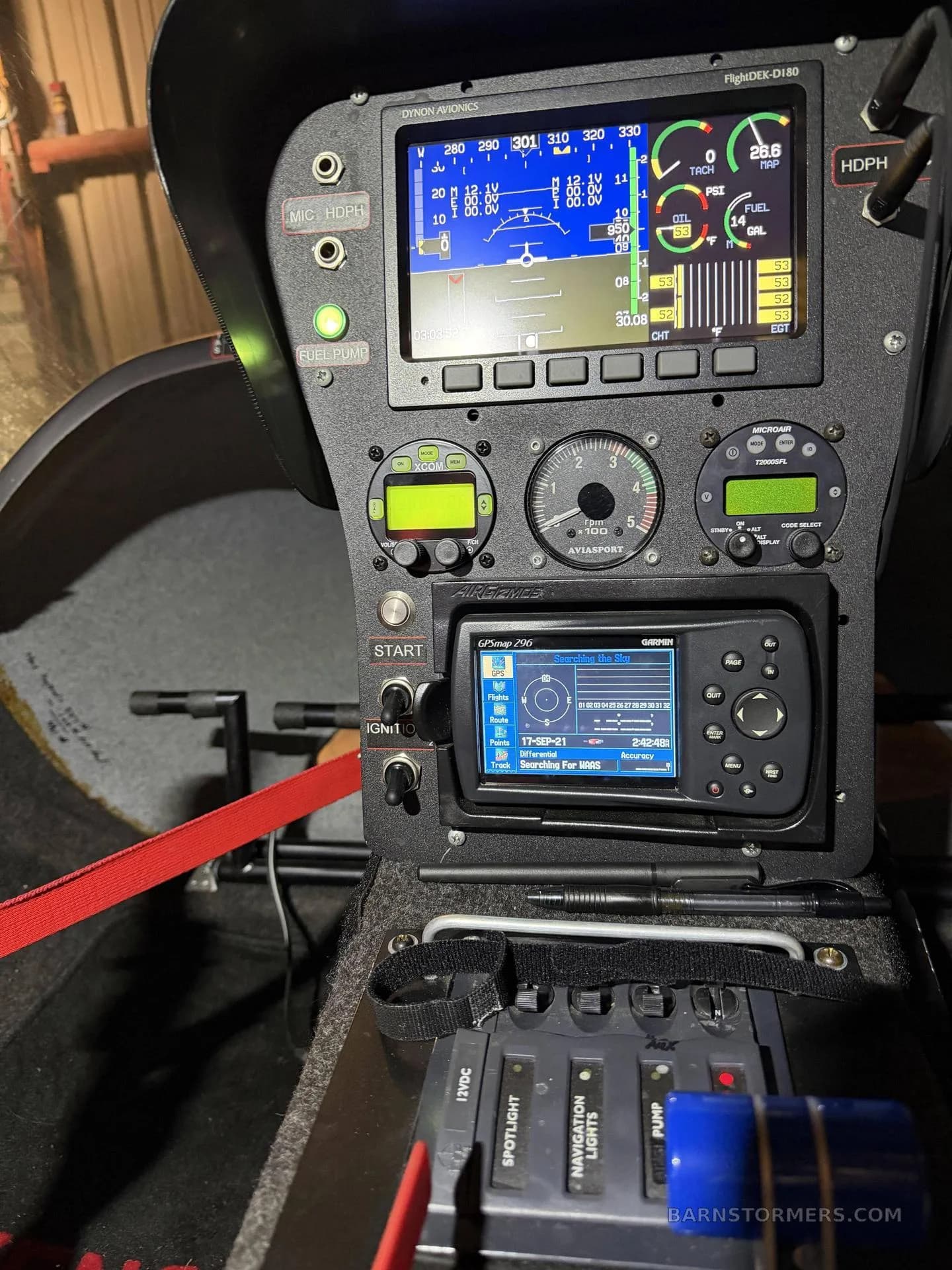A close-up of the autogyro's instrument panel displays multiple digital screens showing flight data, engine parameters, and a GPS unit.