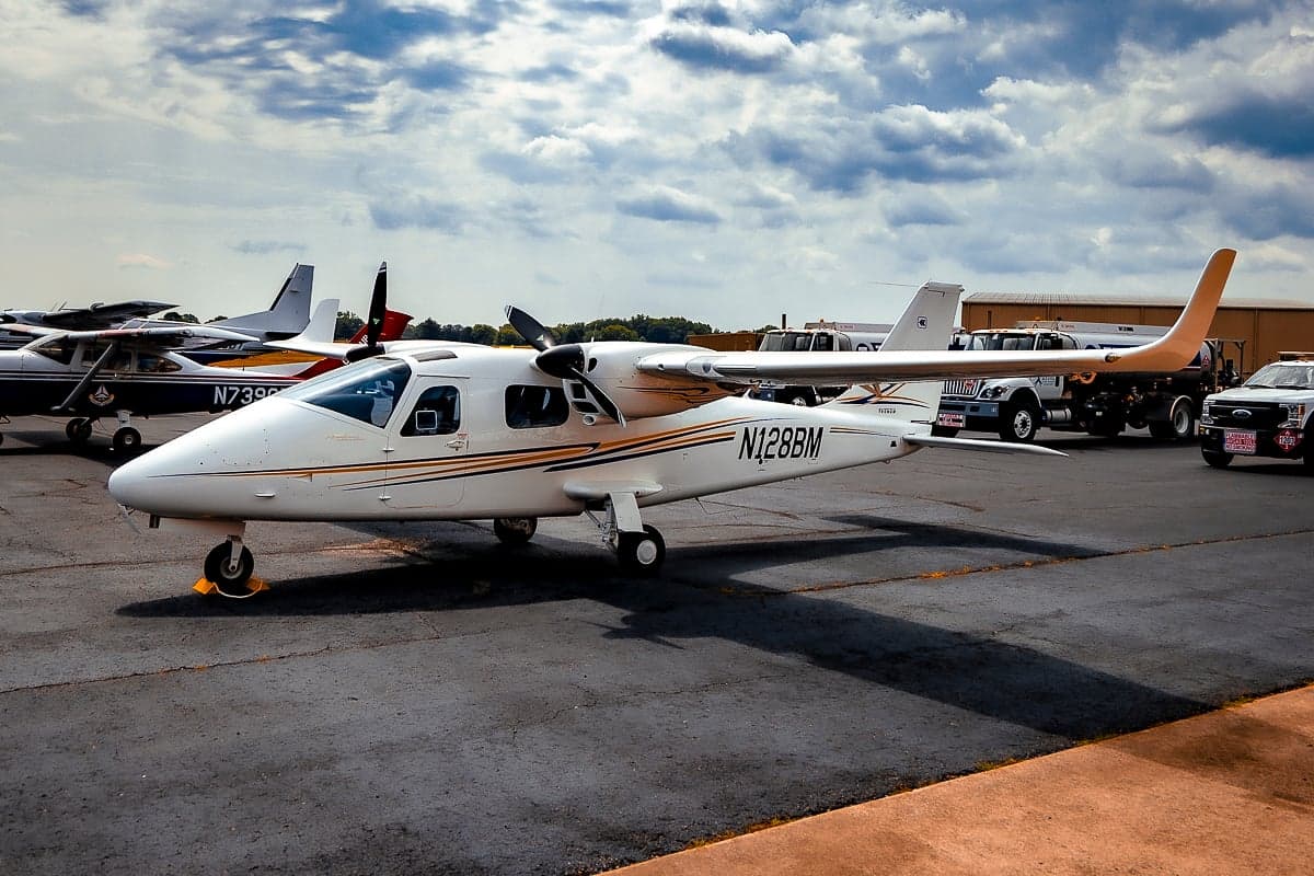 A Tecnam P2006T with registration N128BM is parked on the tarmac at an airport.