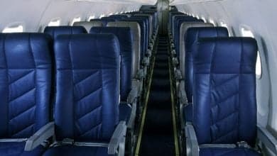 Interior view of an aircraft cabin with rows of blue seats.