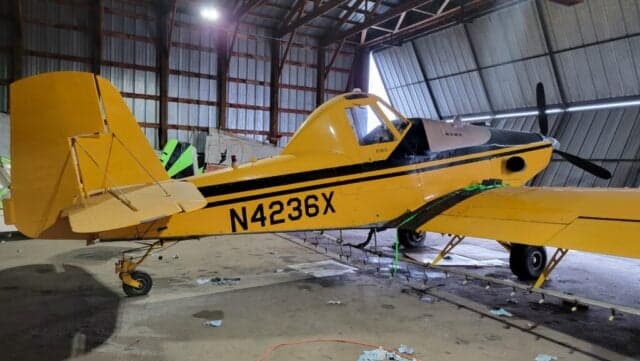 A yellow and black Air Tractor AT-400 sits inside a hangar.