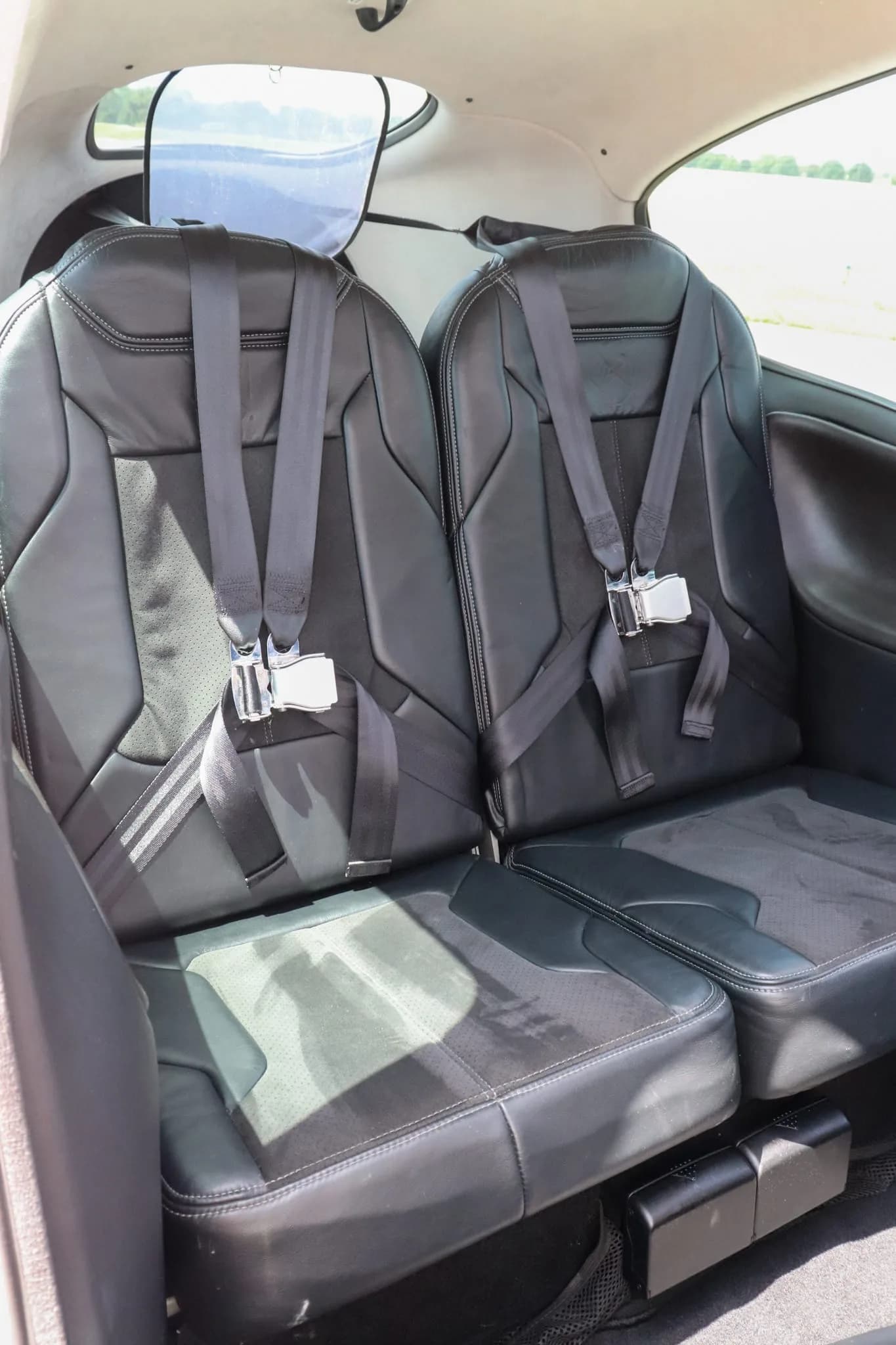 The black leather rear passenger seats of the Cirrus SR20 with seatbelts fastened.