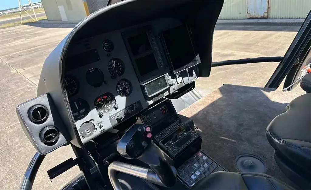The helicopter's instrument panel with analog gauges, digital displays, and flight controls.