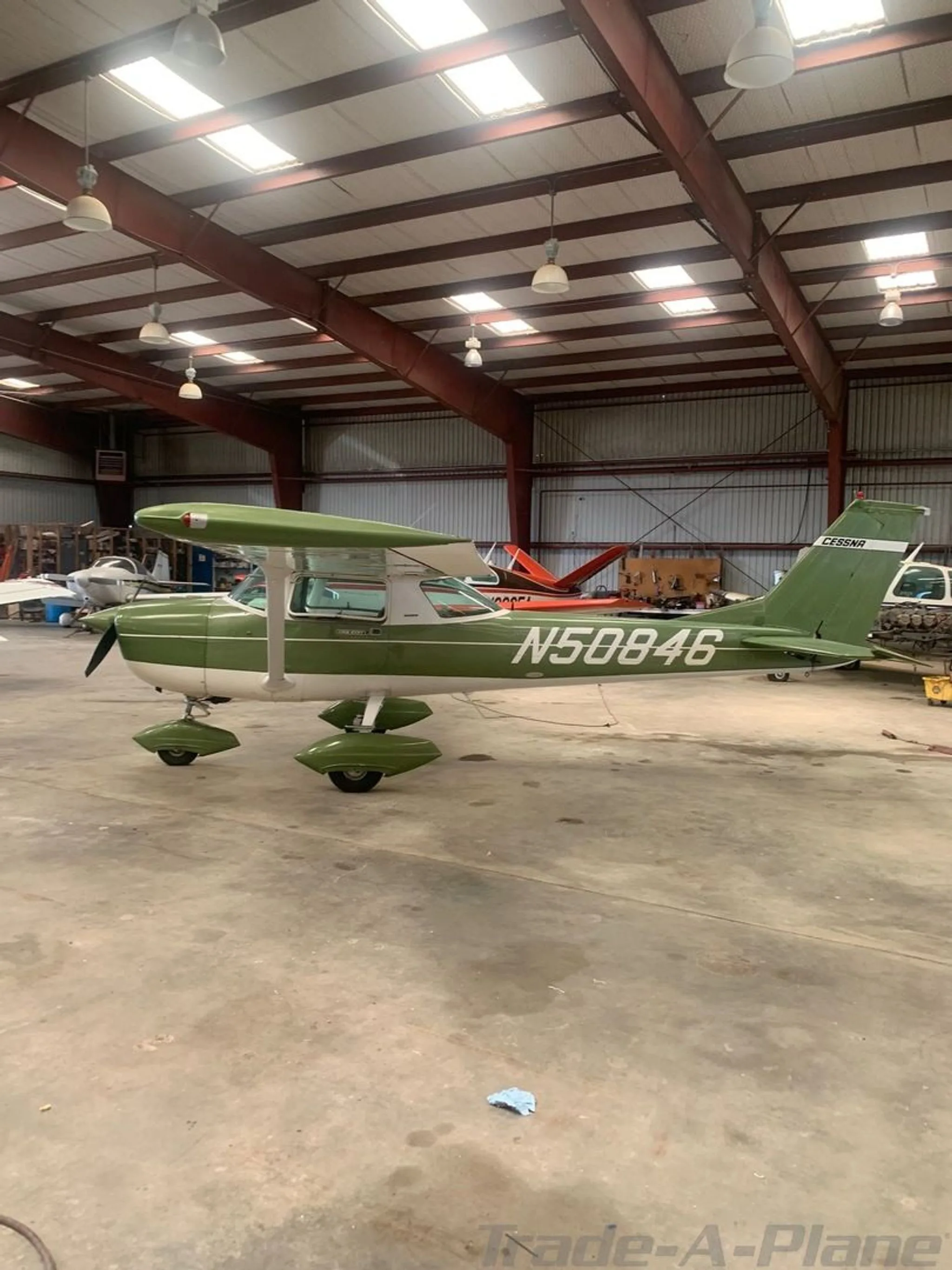 A green and white Cessna aircraft, tail number N50846, is parked inside a hangar.