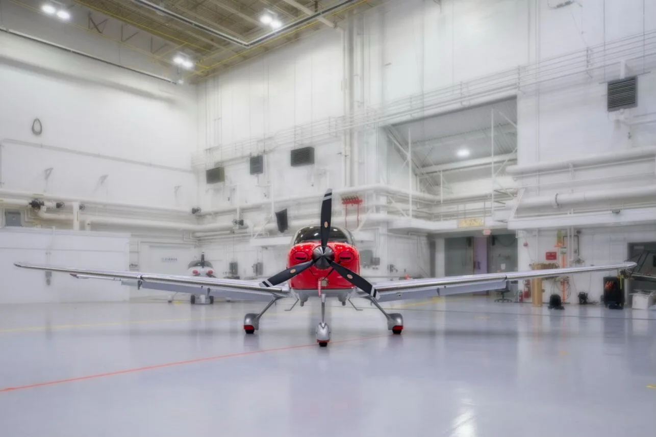 A head-on view of a red and white Cirrus SR22 aircraft with registration N51CW in a hangar.