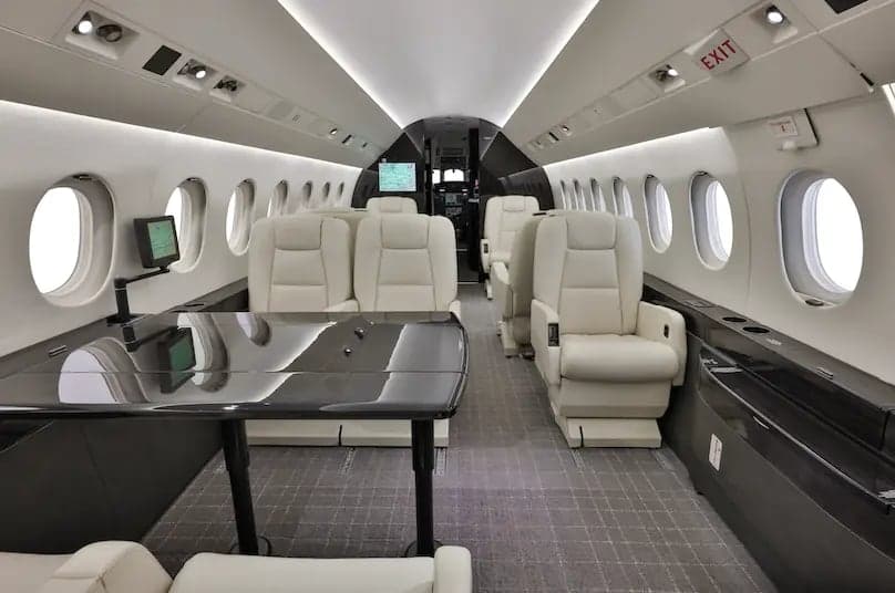 Aircraft cabin with cream-colored seats and a black table.