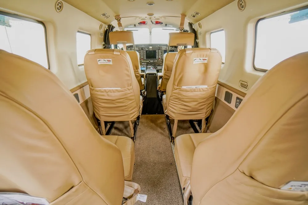 The interior cabin of an aircraft with tan leather seats, viewed from the rear, looking towards the cockpit.
