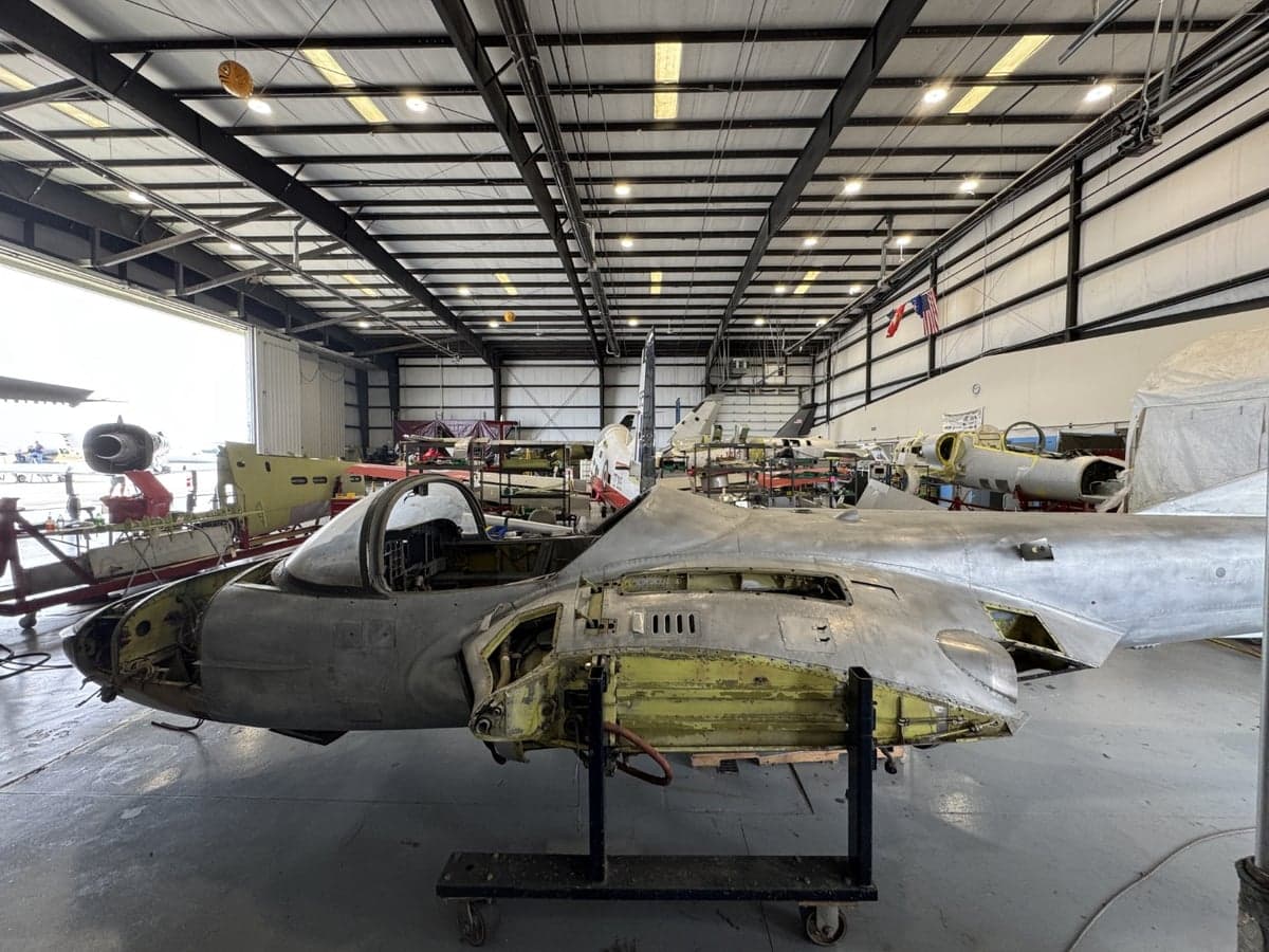 A partially disassembled aircraft in a hangar, side view.