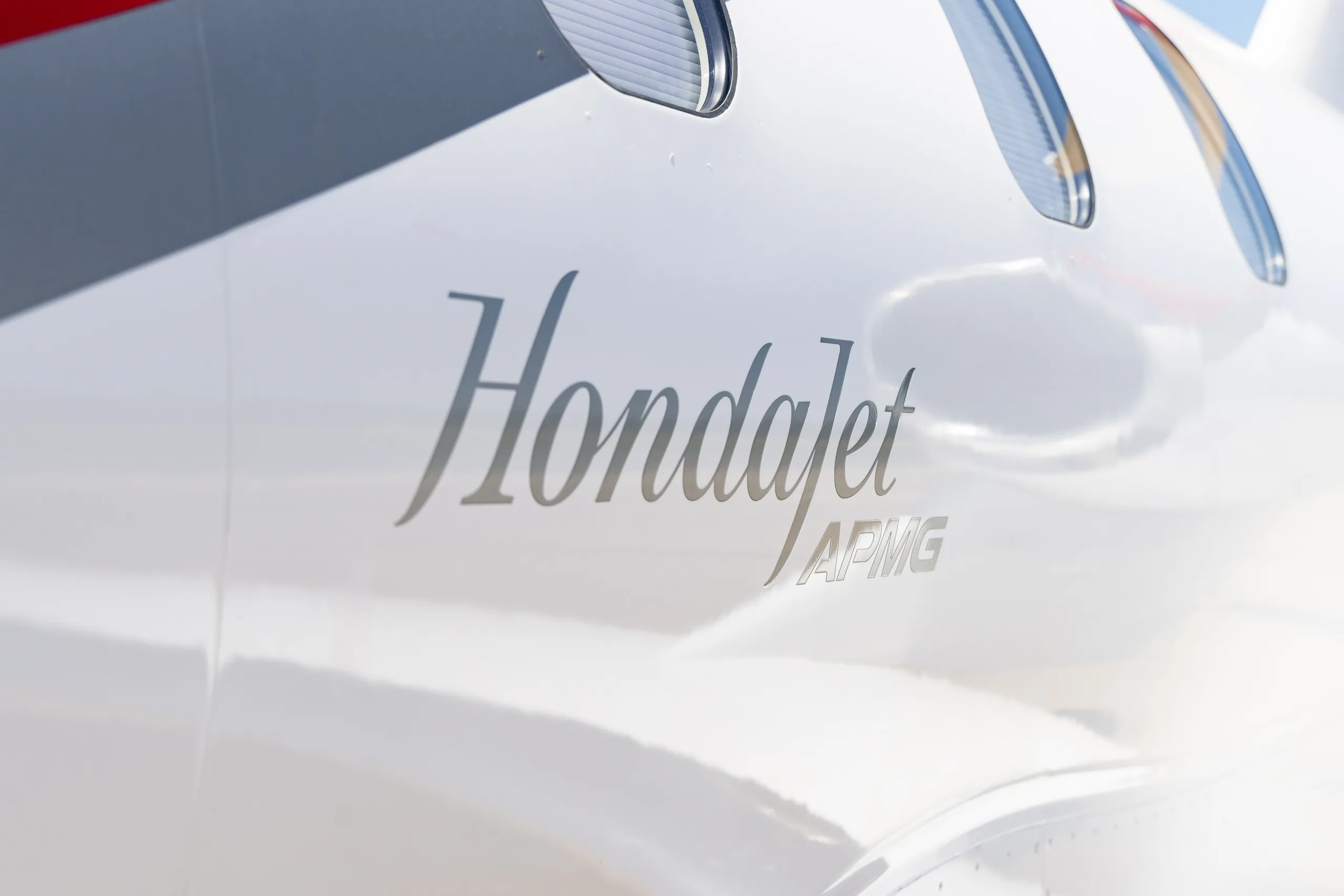 Extreme close-up of the "Hondajet APMG" text on the white fuselage of the aircraft.