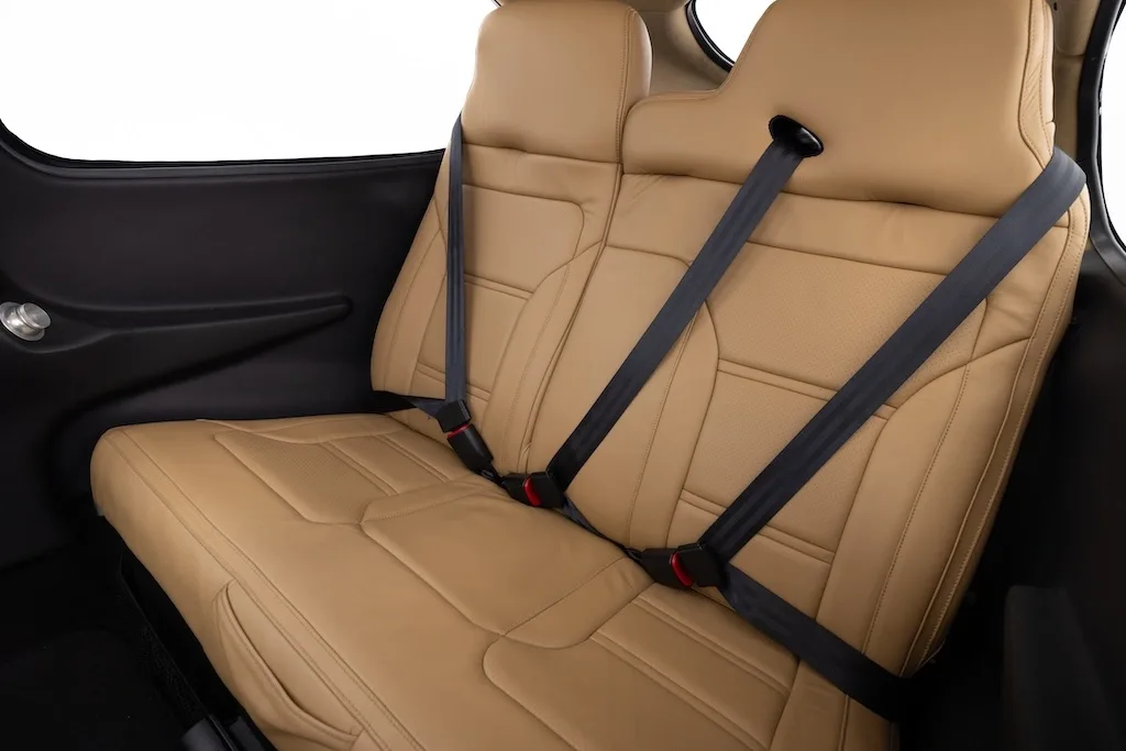 A close-up side view of the tan leather rear seats with seatbelts in the aircraft cabin.
