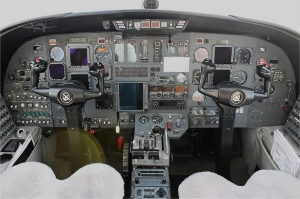 The cockpit of a private jet, featuring a complex instrument panel with multiple screens and controls.