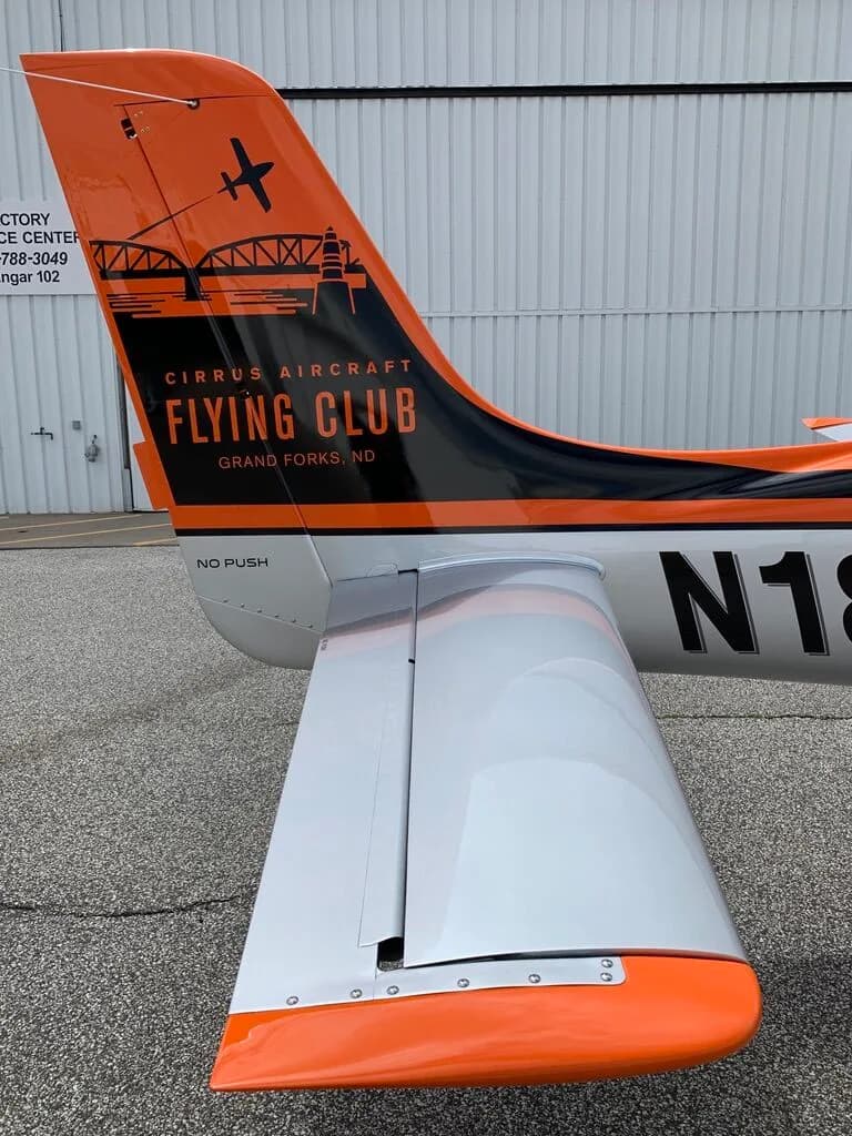 Close-up of the tail of a Cirrus SR20 aircraft, showing the 'Cirrus Aircraft Flying Club' logo and N18GK registration.